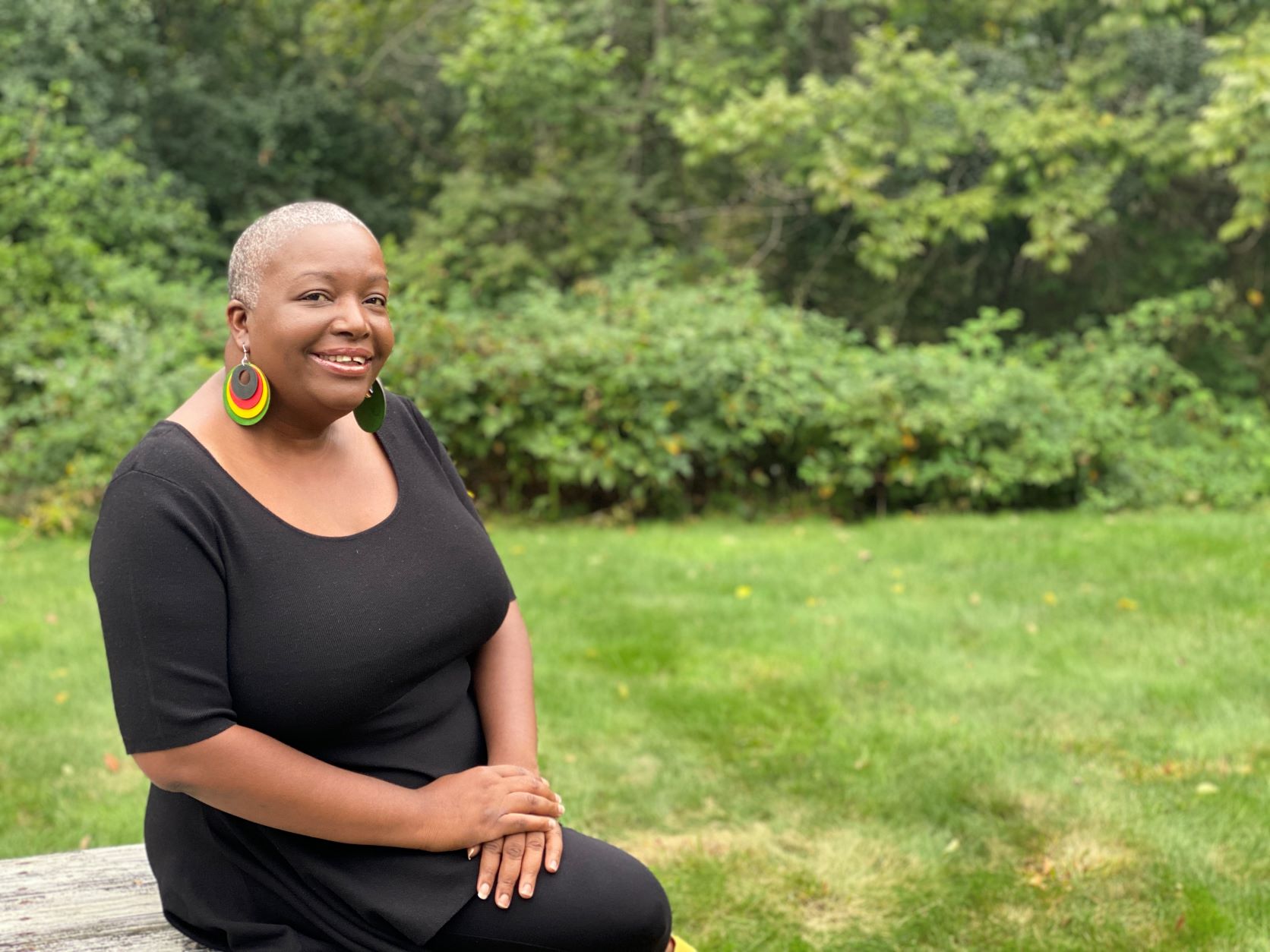 Elaine Dickson MBA '98 leaning against picnic table in black dress