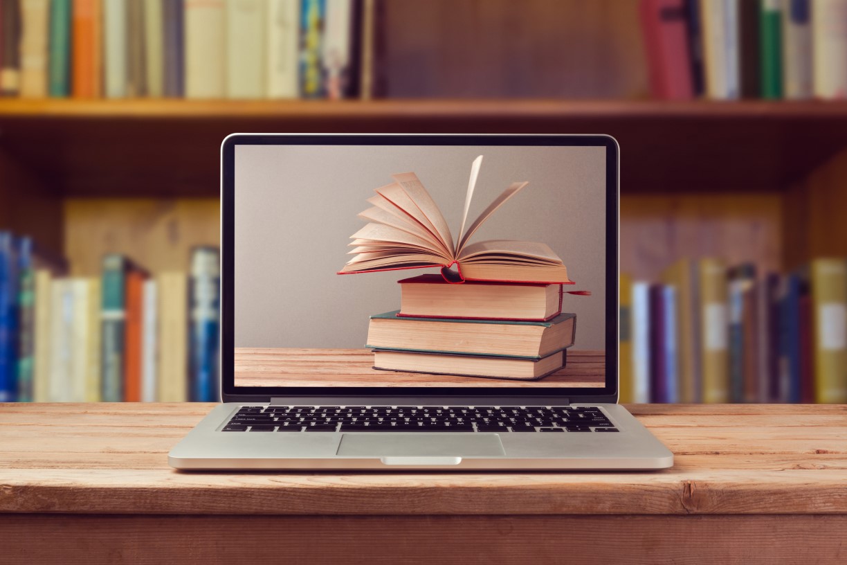 Laptop computer with a screen image featuring a stack of books