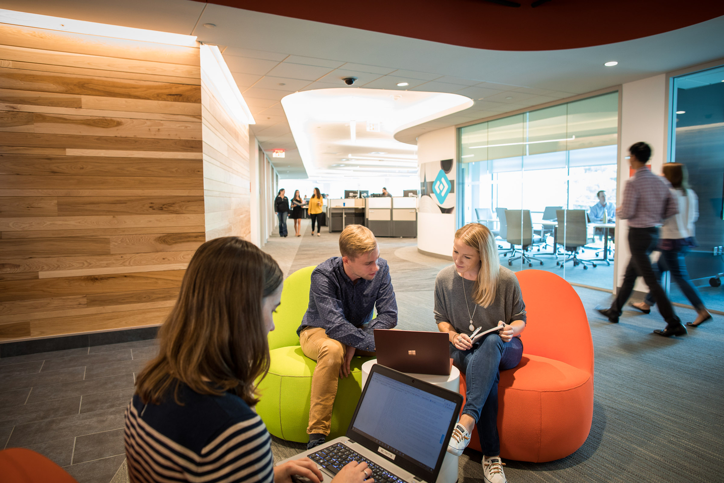 Employees sitting on chairs and collaborating in an office hallway