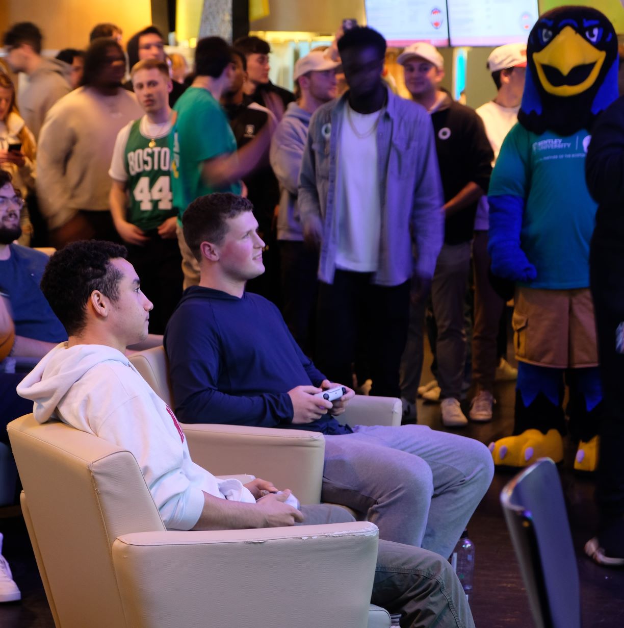 Bentley student Andrew Lussier ’26 competes in the CLTX Shamrock Showdown Collegiate NBA 2K Tournament against a Northeastern student in front of a crowd at Harry's Pub at Bentley