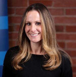 Headshot of professor Erin Flynn, wearing a black crewneck sweater.