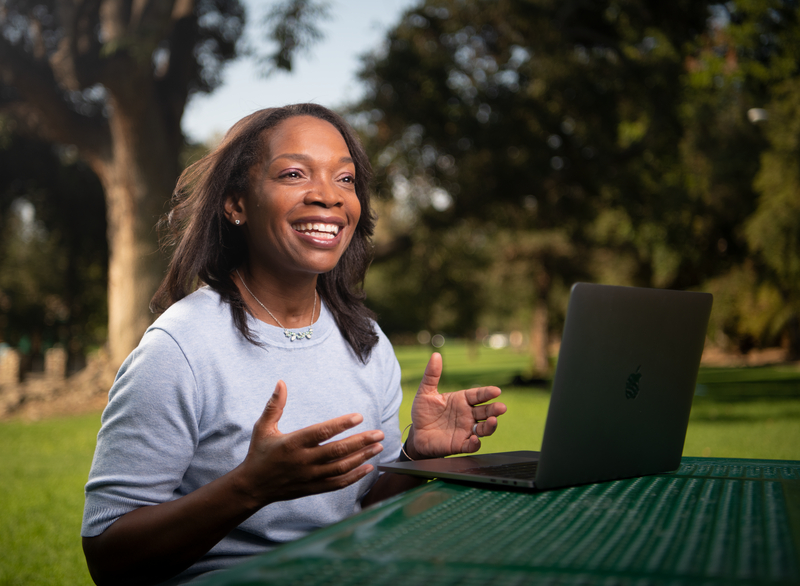 Pauline Callender Han smiling at table with laptop