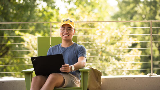 student sitting outside studying on his laptop