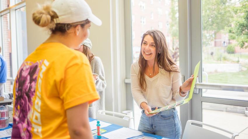 A student speaks with someone them her a form