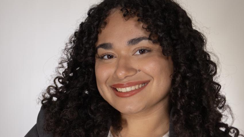 Kary wearing a dark gray blazer and white blouse smiling at the camera