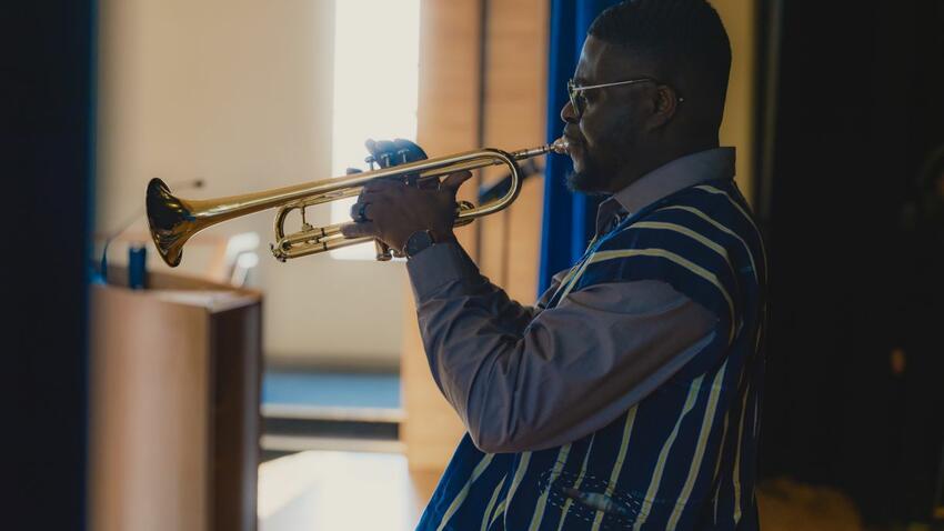 A trumpet player performs at a talent show as part of the Bentley MLK social justice program