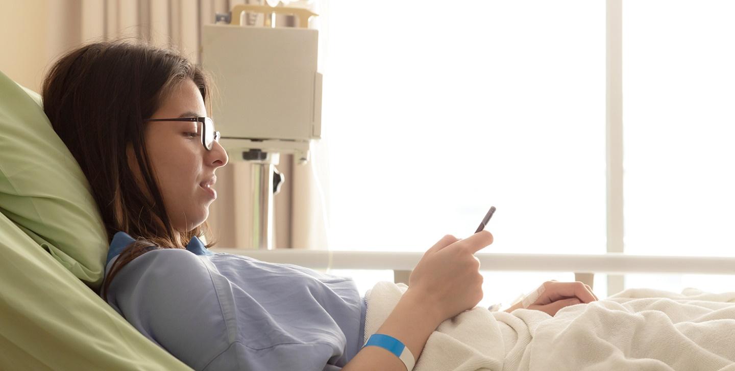 Teen girl in hospital bed looking at her phone