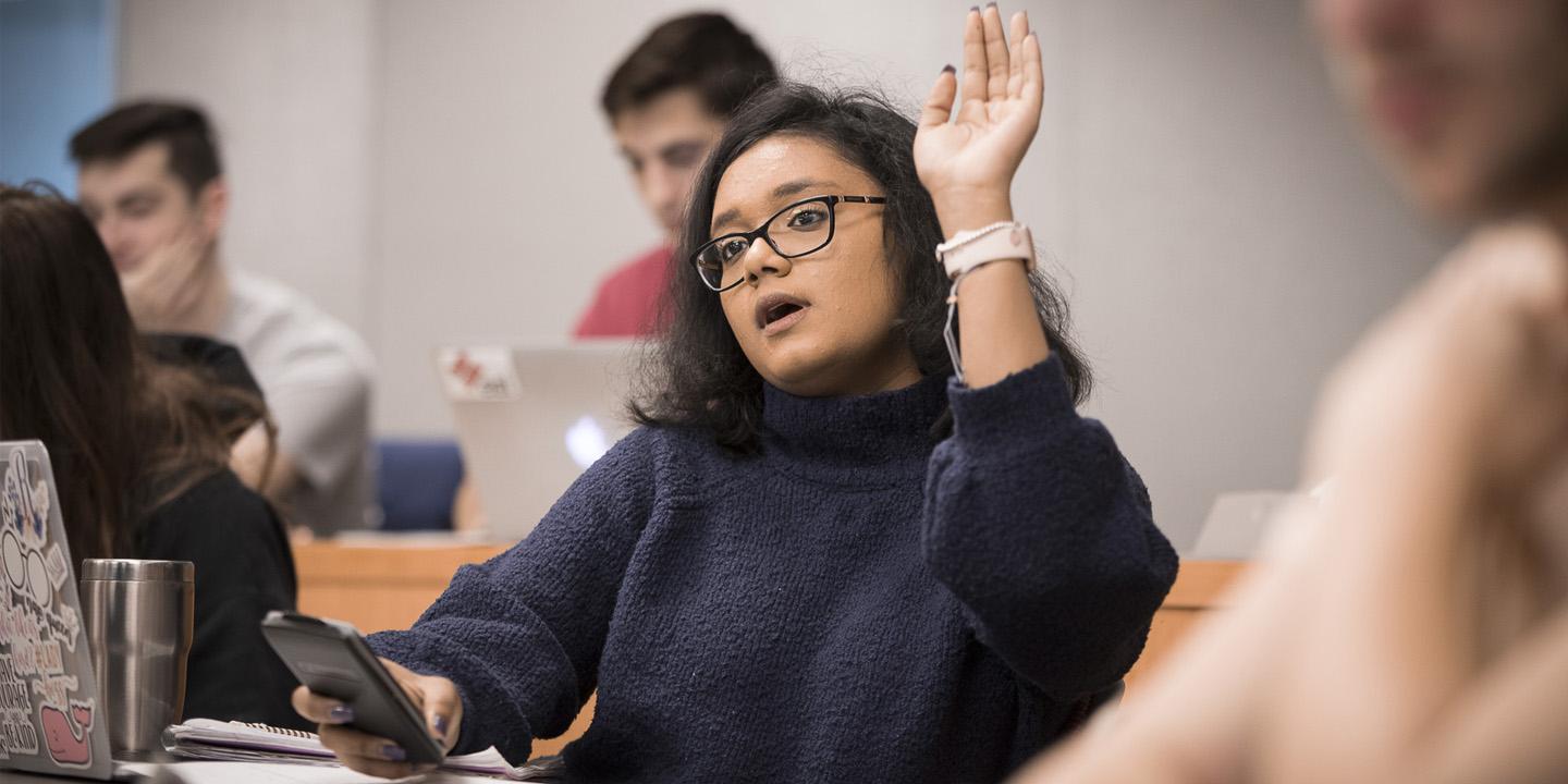 student in classroom raising hand