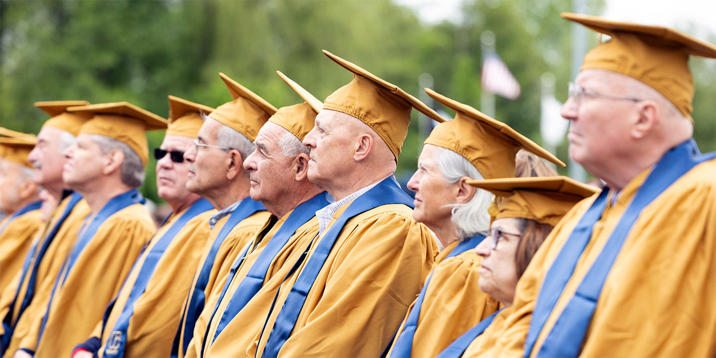 older alumni celebrate reunion with trees in the background