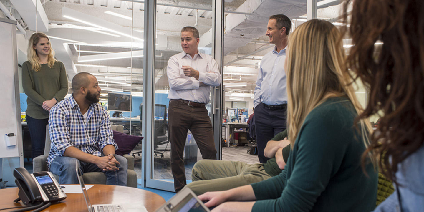 group of people standing around talking in office setting