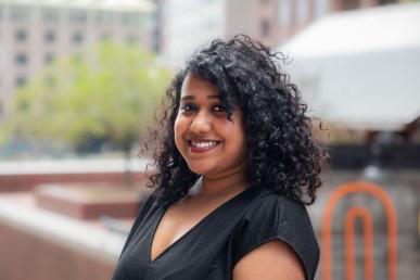 Ankita Dutta standing in front of Boston City Hall wearing black V-neck shirt and smiling