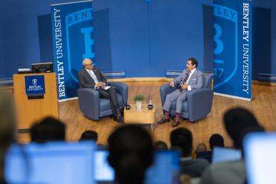 Bentley President E. LaBrent Chrite sitting across from the Ambassador of Bahrain on stage in armchairs in front of an audience