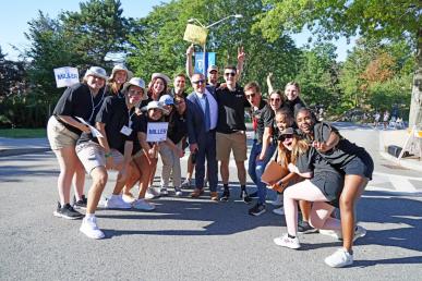 A group of Bentley orientation leaders wearing black t-shirts and holding signs to welcome the Class of 2026