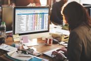 Woman typing on laptop with a spreadsheet open